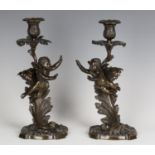 A pair of mid-19th century French brown patinated cast bronze figural candlesticks, each scrolling