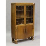 An Art Deco oak glazed side cabinet with carved and fluted panels, on turned supports, height 153cm,