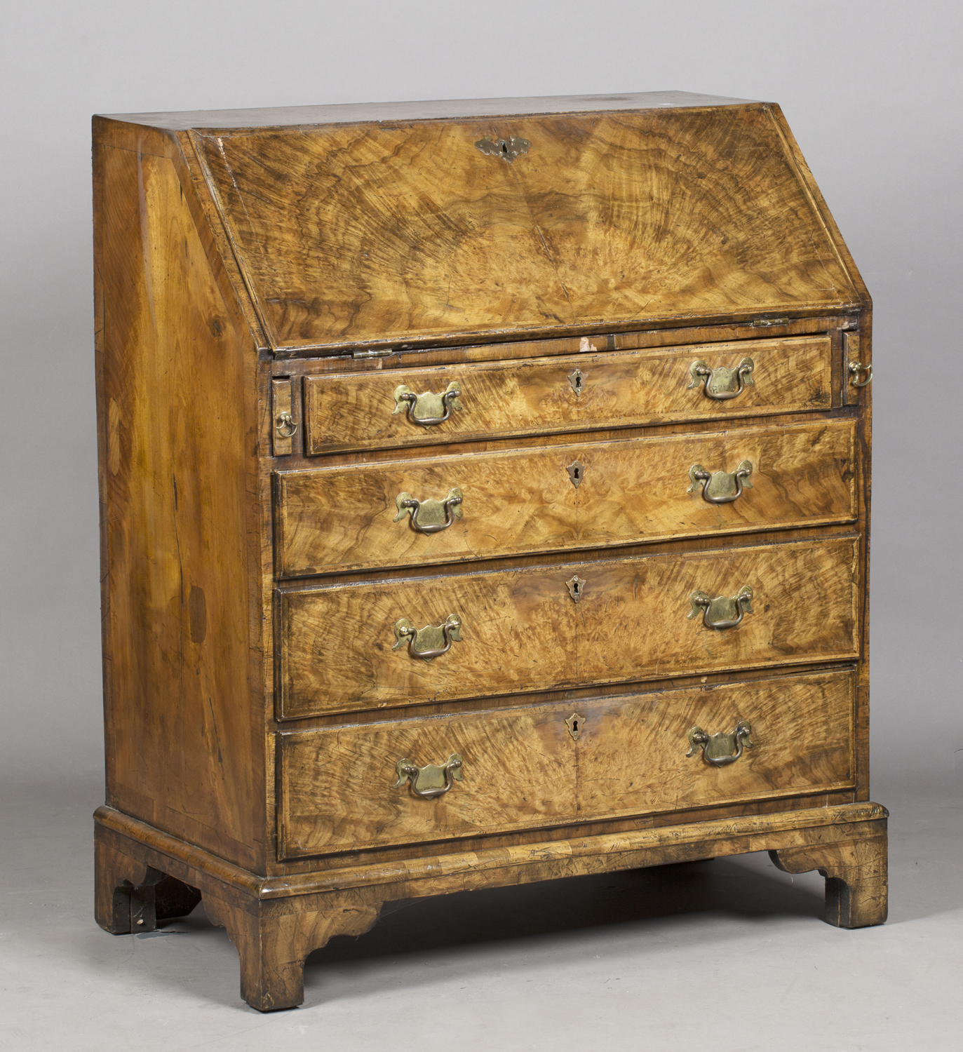 A George I walnut bureau with feather banded borders, the fall-flap enclosing a fitted interior,