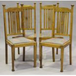 A set of four Edwardian Arts and Crafts oak framed dining chairs with pierced splat backs and drop-