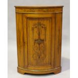 An Edwardian Neoclassical Revival satinwood bowfront corner cabinet with overall inlaid fruit-