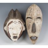 An African carved and painted mask of elongated form, height 34cm, together with another similar