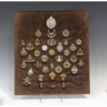 A framed and glazed display of various military and other cap badges, including a Victorian 2nd