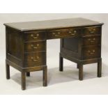 A George V stained oak twin-pedestal desk, fitted with seven drawers, on block legs, height 77cm,