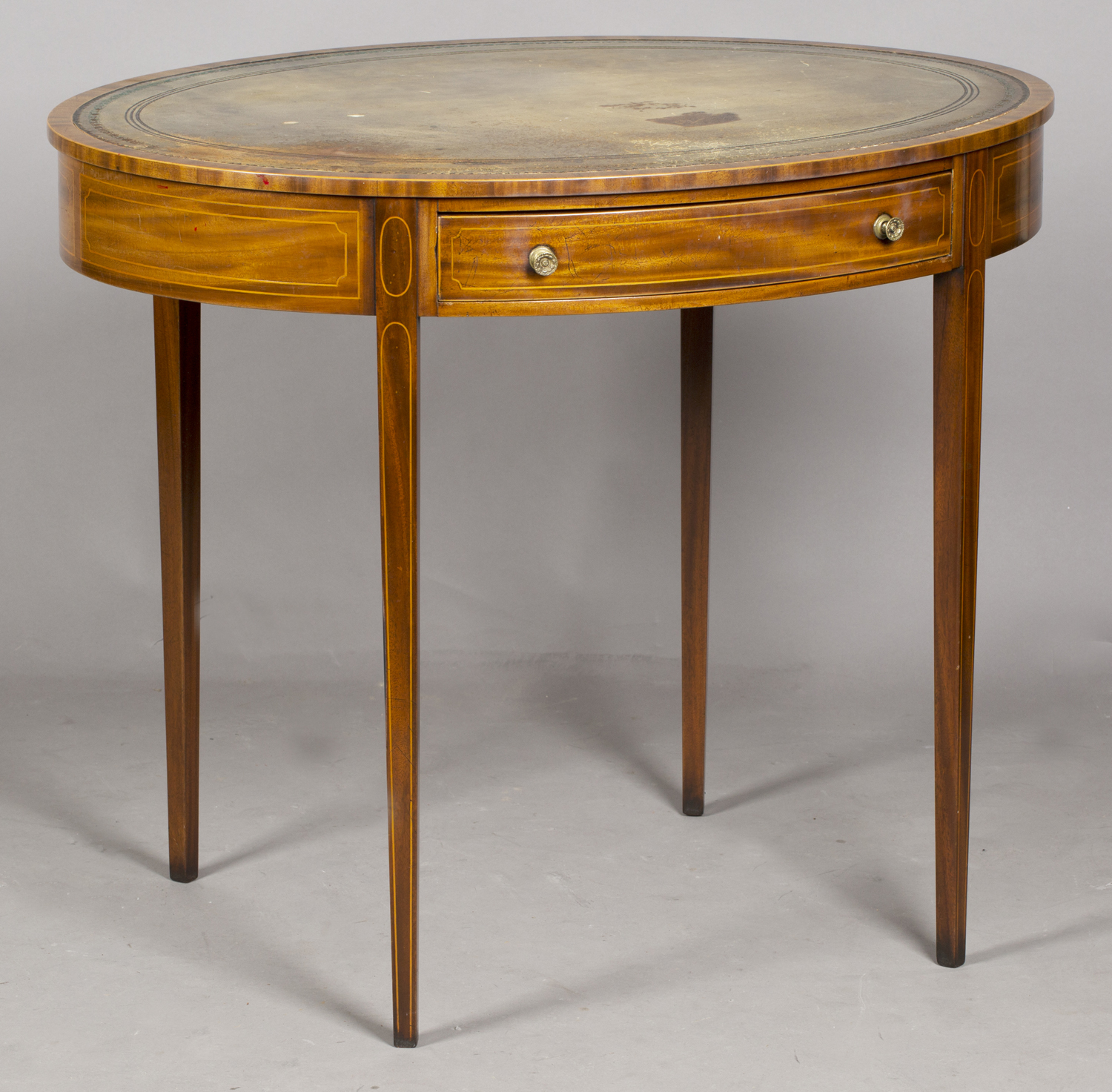 A George III mahogany oval writing table with overall boxwood stringing and inset green leather top,