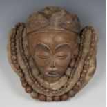 An African carved wooden mask, the cloth neckpiece with applied wooden bead necklace, height 30cm.