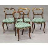 A set of four mid-Victorian rosewood framed spoon back dining chairs with carved centre rails and