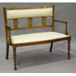 An Edwardian walnut framed two-seat salon settee with boxwood line inlay and upholstered in