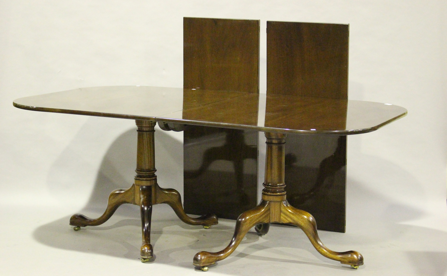 A late 20th century George III style mahogany twin-pedestal dining table, the top with two extra