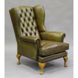 A 20th century George III style wing back armchair, upholstered in buttoned khaki leather, on