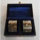 A pair of Edwardian Art Nouveau influenced napkin rings with stylistic floral motif, makers mark GH,