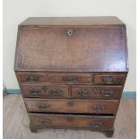 A George III oak bureau of small proportion with fall front and fitted interior over four short