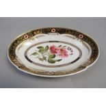 A Spode lobed oval dish, the centre painted with dog roses within a dark blue and gilt border having