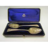 A pair of boxed silver berry spoons, Georgian with later Victorian embossed and chased decoration,