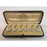 An Edwardian period boxed set of six mother of pearl gold backed circular shirt studs with blue