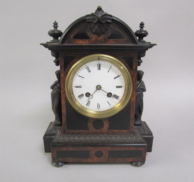 A 19c ebonised mantel clock with figurative pilaster mounts, burr wood crossbanding and inlaid