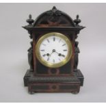 A 19c ebonised mantel clock with figurative pilaster mounts, burr wood crossbanding and inlaid