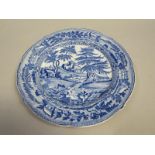 A Blue and white plate printed with a rural scene of a family with dog and cottages, and figures and