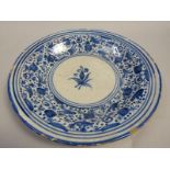 A Faience dish painted in blue with stylised flowers with a blue line border, a/f, 30cm diam.