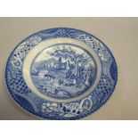 A blue and white soup plate printed with a scene of two figures in conversation beneath a tree and