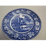 A blue and white plate printed with a scene of travellers and a horse resting bedside a ruined
