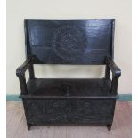 A period oak monks bench, the face of the table top circular carved when open, supported on the