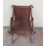 A 19c oak jointed armchair with solid back panel and seat, having scrolling shaped arms and