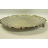 A contemporary silver salver with a raised border, supported on three scrolling feet, makers mark