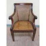 An early 19c mahogany scroll armchair with caned back and seat on straight square tapering legs.
