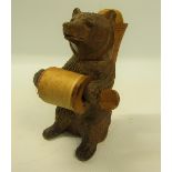 A late 19c/early 20c carved wooden bear pin cushion cotton holder, the bear seated carrying the