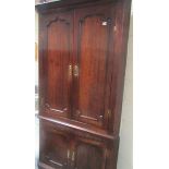 A George III oak standing corner cupboard of substantial form, the upper section fitted shelves