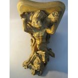 A 19c carved wood and stucco wall bracket, the stand supported by a male form riding upon a