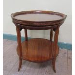 An Edwardian satin wood veneered two tier circular tea table with ebony line, having a lift off