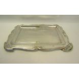 An Edwardian silver table tray with Art Nouveau influence, having a shaped border with embossed leaf