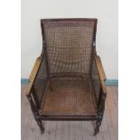 A late 19c mahogany framed bergere armchair with baluster turned arm supports, supported on ring