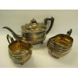 A late Georgian three piece silver tea service, half lobed with angular handles and gilt lined