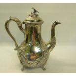 A Victorian silver coffee pot embossed and chased with panels of flowers and with open scroll
