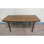 A 1970's teak low table of rectangular shaped form with two pull out end shelves and supported on