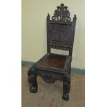 A 19c Indian side chair with a figurative carved back panel within profuse leaf and flower under a