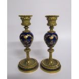 A pair of late 19c ormolu and ceramic candlesticks, the ceramic knops with jewelled gilt wreath