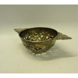 A George III silver quaich shaped bowl, pierced and floral embossed and chased with two side