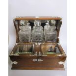 A late 19c oak three bottle locking tantalus. The tantalus has silver plated cut mounts and