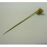 An Edwardian gold stick pin with a dog's head terminal, having ruby eyes, collar with bell. 9.5cms