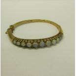 A gold bangle set with eleven graduated opals - 23g overall.