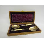 A pair of Victorian silver plated serving spoons with gilt lined bowls, chased with bands of leaf