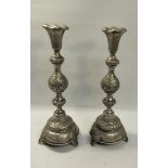 A pair of 19c Russian silver candlesticks with embossed double knop columns on circular stepped