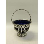 An Edwardian silver sugar basket of pierced circular form with a swing handle and blue glass
