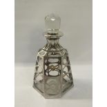 An early 20c clear glass hexagonal facet tapering decanter, silver cased with open ovals and