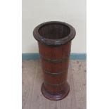 A late 19c mahogany stick stand of cylindrical form, brass banded and supported on a circular