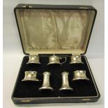 A seven piece silver condiment set comprising of four salts, two peppers and one mustard. Makers